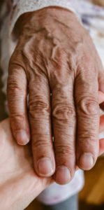 main d'une personne âgée reposant sur la main d'une personne plus jeune pour exprimer la relation à la fin de vie